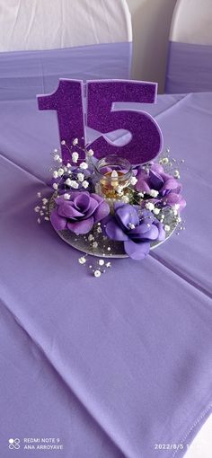 a purple table cloth with flowers and the number fifteen on it's centerpiece