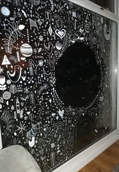 a large black and white drawing on the side of a wall next to a chair