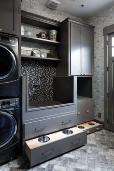 a washer and dryer in a room with grey walls, cabinets and drawers