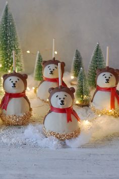 there are snowmen made to look like teddy bears with lights on them and trees in the background