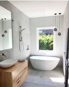 a bathroom with a tub, sink and large mirror in it's center window