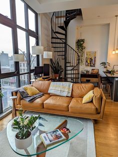 a living room filled with furniture next to a tall glass window covered in lots of windows