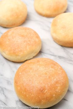 several round bread rolls lined up on a marble surface