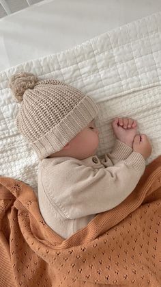 a baby laying on top of a bed next to a blanket