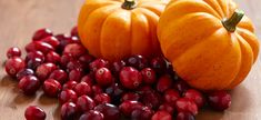 two pumpkins and some cranberries on a table