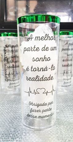 a glass with writing on it sitting on a table next to other glasses and cups