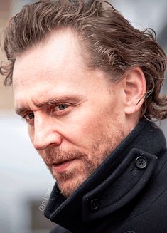 a close up of a person wearing a coat and looking at the camera with a serious look on his face