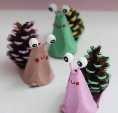 three little pine cones with googly eyes are sitting next to each other on a table