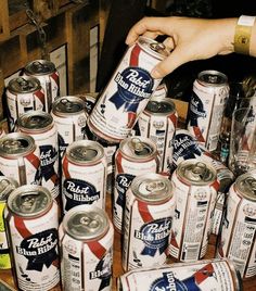 many cans of beer are stacked on top of each other and being held by a person