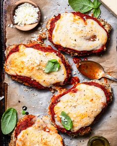 three meatloafs with sauce and herbs on a sheet of baking paper next to two spoons