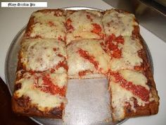 a square pizza on a metal pan with several slices cut out and ready to be eaten