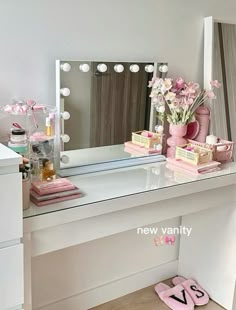 a vanity with flowers and pink slippers on the floor in front of a mirror