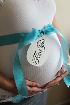 the pregnant woman is holding her belly with a blue ribbon around it's waist