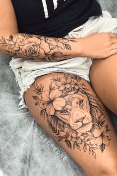 a woman with a lion tattoo on her thigh, sitting in front of a bed