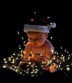 a baby wearing a santa hat surrounded by christmas lights