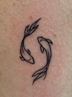 a small tattoo on the back of a woman's shoulder with two fish swimming in it