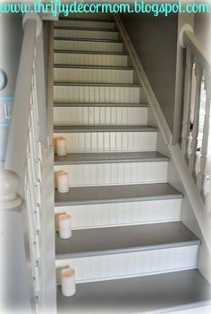 some candles are sitting on the steps in front of a staircase that is painted white