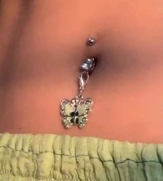 a woman's stomach with a butterfly charm attached to the belly and dangling from it