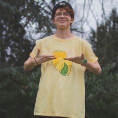 a young man in a yellow shirt holding out his hands