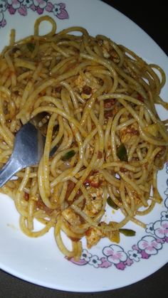 a white plate topped with spaghetti and meat