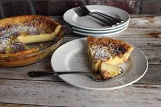 a pie sitting on top of a wooden table next to plates and utensils