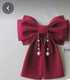 a red bow tie with pearls hanging from it's side on a white wall