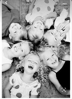 black and white photograph of children laying on the ground with their mouths open, smiling