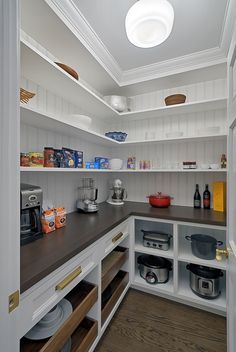 a kitchen with white cabinets and wooden counter tops, including pots and pans on the shelves