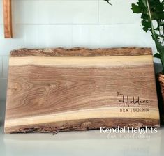 a wooden cutting board sitting on top of a counter next to a potted plant