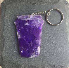 a purple cup is sitting on top of a black stone with a keychain