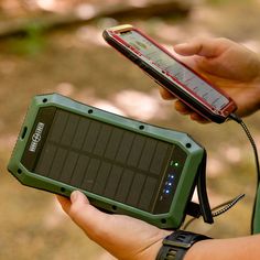 a person holding a solar powered device in their left hand and an mp3 player in the other hand