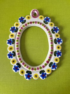 a white and blue flowered frame hanging on a green wall