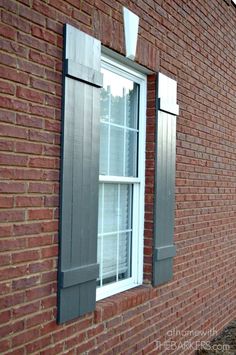 a red brick building with two windows and shutters