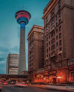 a very tall tower towering over a city next to other tall buildings at night time