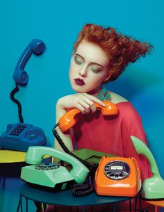 a woman sitting at a table with an orange telephone