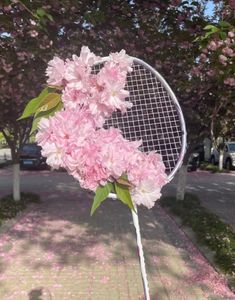 a tennis racket with pink flowers on it is in the grass near some trees