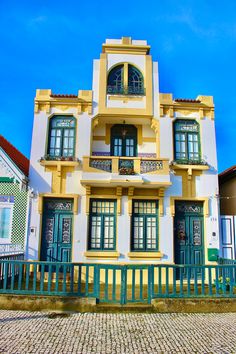 a large yellow and white building with green shutters on the front, and blue sky in the background