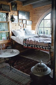 a room with a bed, table and pictures on the wall above it in an old fashioned log cabin