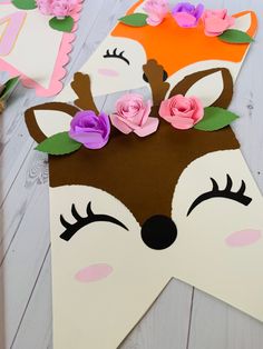 paper flowers are placed on top of a deer's head cut out of cardboard