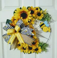 a sunflower wreath on the front door with a bee and checkered ribbon around it