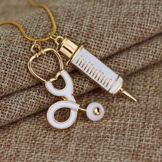 a gold necklace with a pair of scissors and a needle on it's end