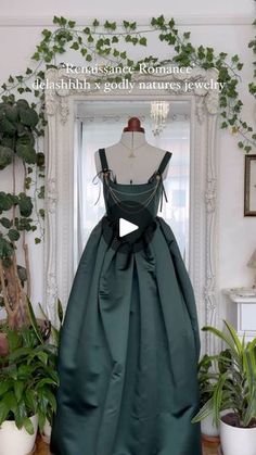 a green dress sitting on top of a mannequin next to potted plants