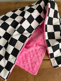 a black and white checkered jacket laying on top of a wooden floor with pink lining