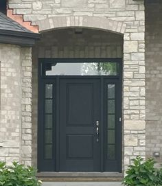 a black front door and some bushes outside