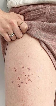 a woman's thigh with small stars on it and her hand resting on the thighs