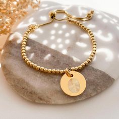 Our stunning fingerprint disc bracelet is the perfect keepsake to cherish forever! Our beautiful range of fingerprint keepsakes make a gorgeous way to capture precious memories of loved ones. See how you can start creating yours with our handy Guides & How To's This beautiful gold disc charm is perfect for engraving your loved ones finger print, along with optional personalised text on the back. The yellow gold vermeil disc charm measures 17mm across the front of the disc and sits centrally on a Personalized Round Bracelets For Keepsake, Carton Texture, Disc Bracelet, Beautiful Range, Finger Print, Gold Disc, Bracelet Diy, Precious Memories, Engraved Jewelry