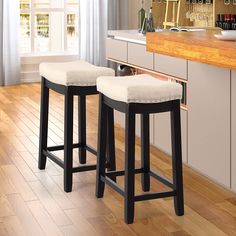 two stools sitting on top of a wooden floor in front of a kitchen counter