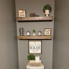 a toilet in a bathroom with two shelves above it and a sign on the wall