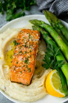 a plate topped with mashed potatoes and asparagus next to a piece of salmon