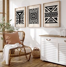 three black and white art prints hanging on the wall next to a wicker chair